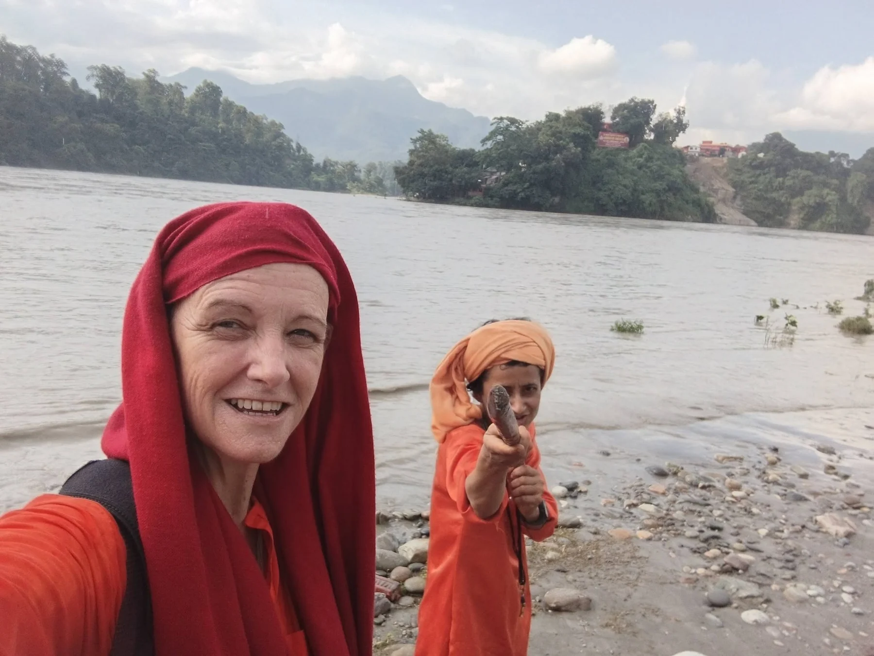 Two women by a river, with hills in the background